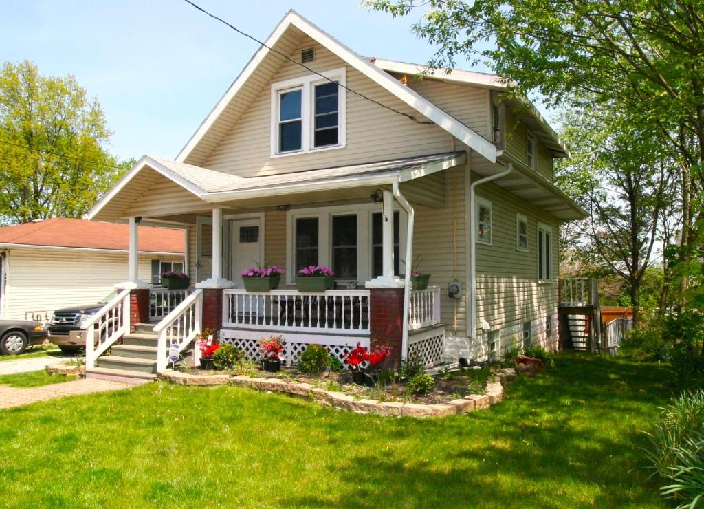 a house with a porch and flowers in the yard at Cheerful 3 BR. 2 Bath, Spacious Family Home in Akron