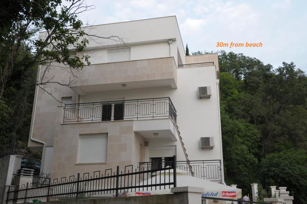 ein weißes Gebäude mit einem Balkon und Bäumen in der Unterkunft Apartments Villa Simonovic in Petrovac na Moru