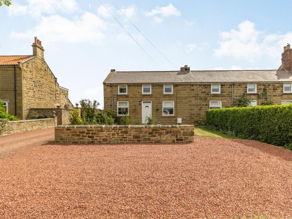 a brick house with a stone wall and a driveway at Seabreeze Cottage in Ashington