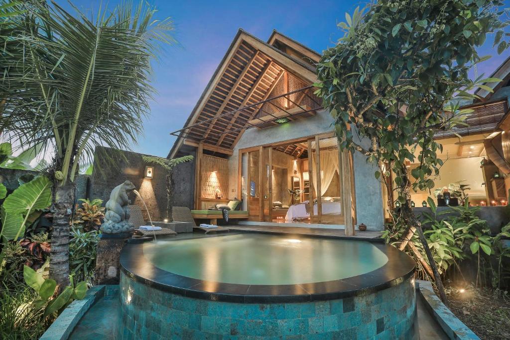 a villa with a swimming pool in front of a house at Wana Bucu Villas by Pramana Villas in Ubud