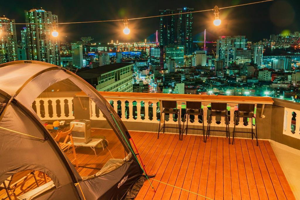 a tent on a balcony with a city skyline at night at Big K House in Busan