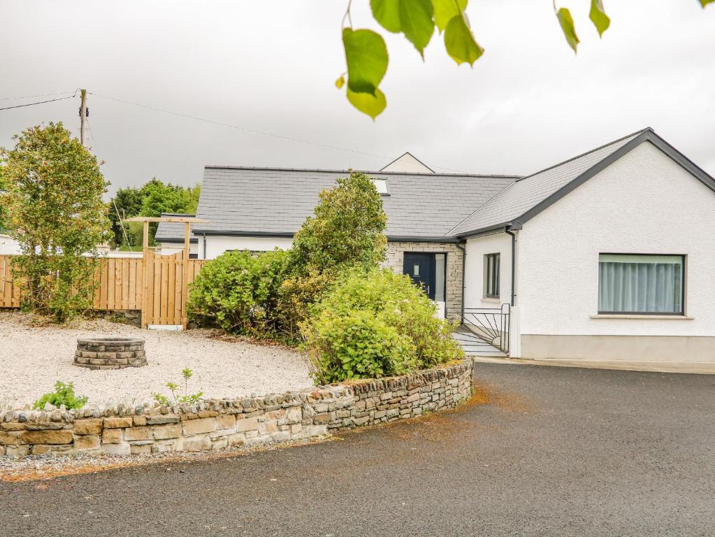 a house with a stone wall in front of a driveway at Wee Andy's in Buncrana