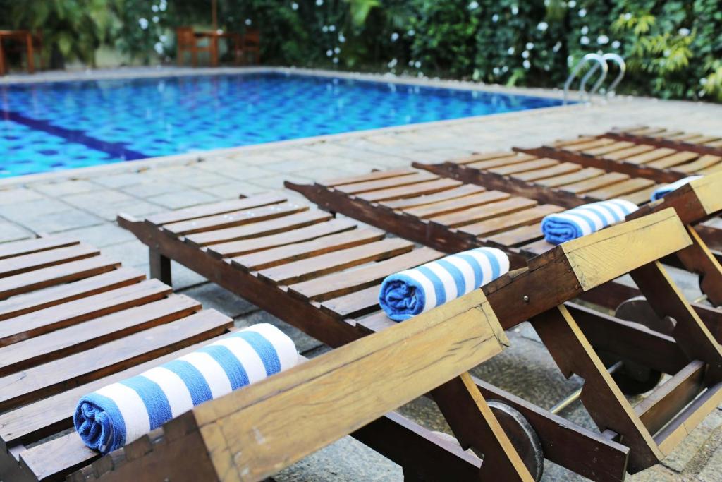 a row of wooden benches next to a swimming pool at Hotel Casamara in Kandy