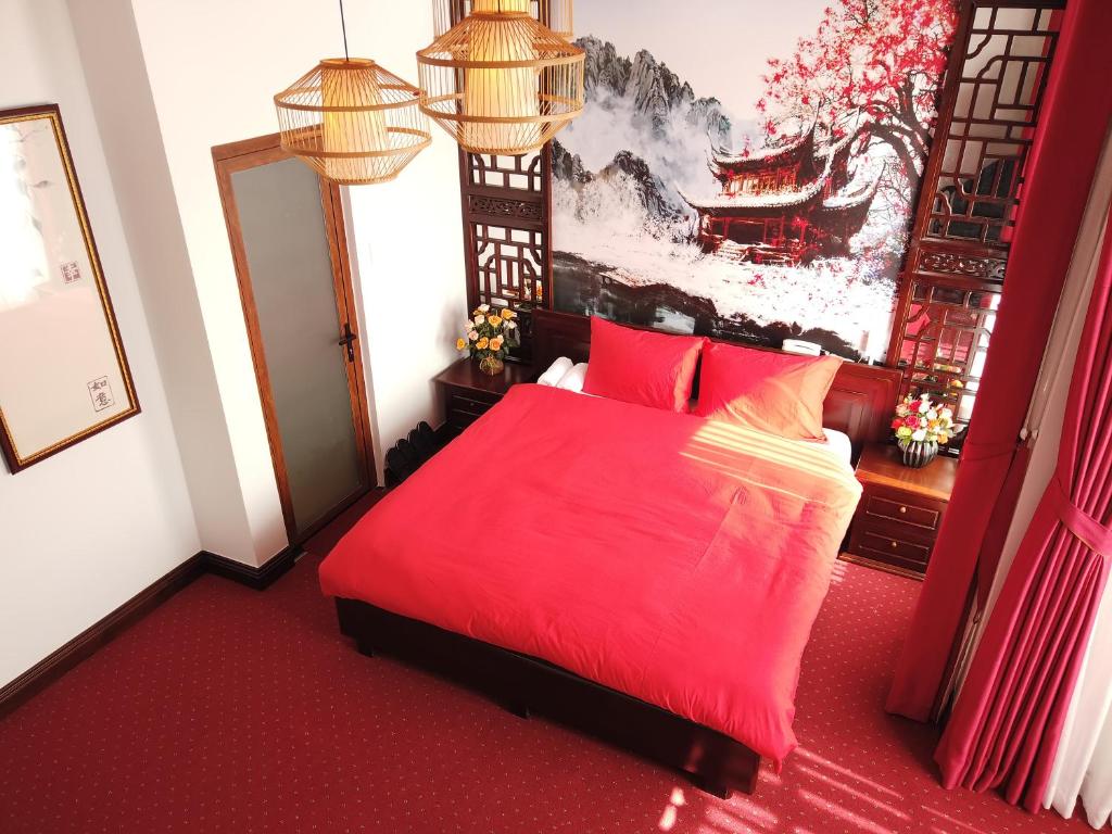 a bedroom with a red bed and a painting on the wall at Free Style Hotel Dalat in Da Lat