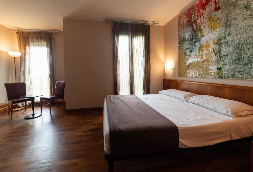 1 dormitorio con 1 cama y una pintura en la pared en HOTEL QUERINI Budget & Business Hotel Sandrigo, en Sandrigo