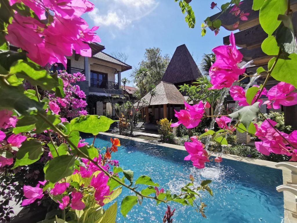 a swimming pool in front of a house with pink flowers at Artoria Dream Villas Bali in Nusa Dua