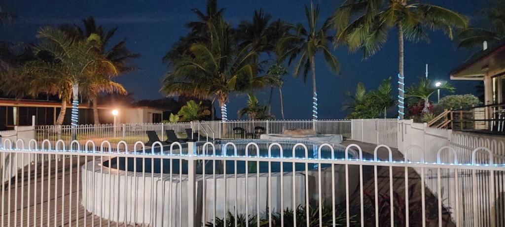 a fence in front of a pool with palm trees at Whitsunday Sands Resort in Bowen