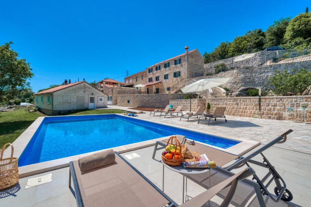 a pool with a table with a basket of fruit next to it at Villa Konavoski Miri in Gruda