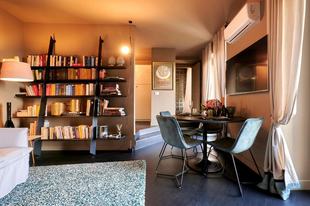 un soggiorno con tavolo, sedie e libreria di My Home For You - Città Alta a Bergamo