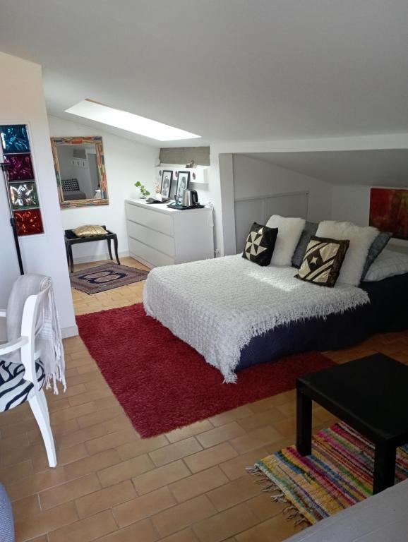 um quarto com uma cama branca e um tapete vermelho em La Mansardiere em Villecroze