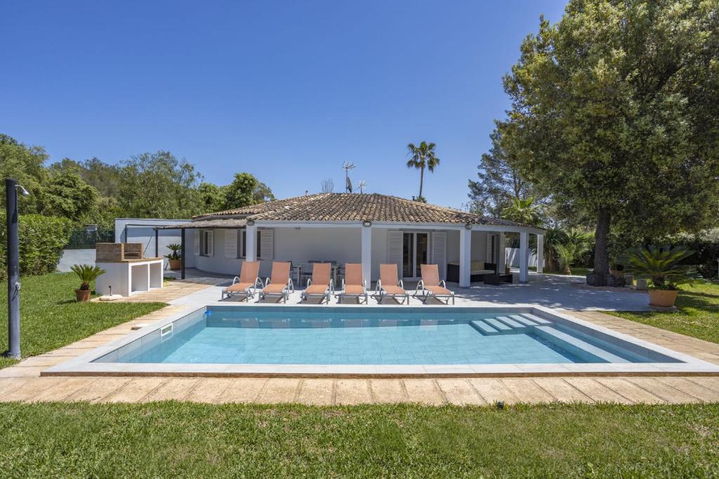 a swimming pool with chairs and a house at Casa Encinar in Crestatx