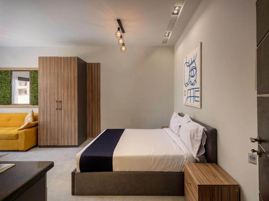 a bedroom with a bed and a yellow couch at Travelholic Residence Golden Gates in Cairo