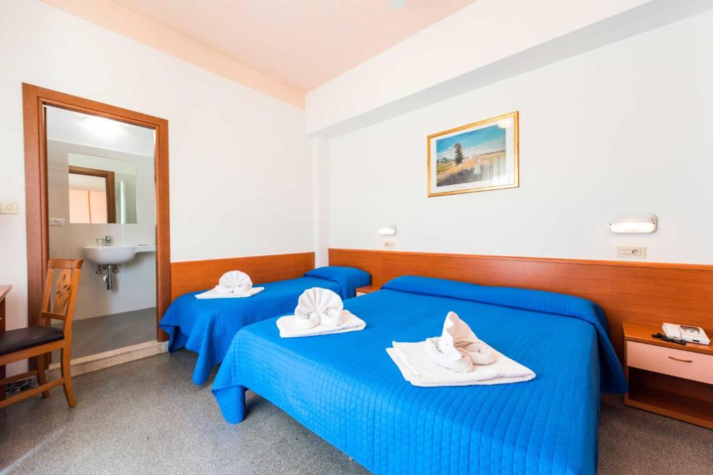 リミニにあるHotel Pacificのベッド2台と鏡が備わるホテルルームです。
