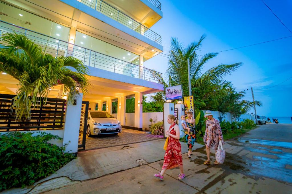 duas mulheres a andar em frente a uma casa em Liyonaa Beach Hotel em Trincomalee
