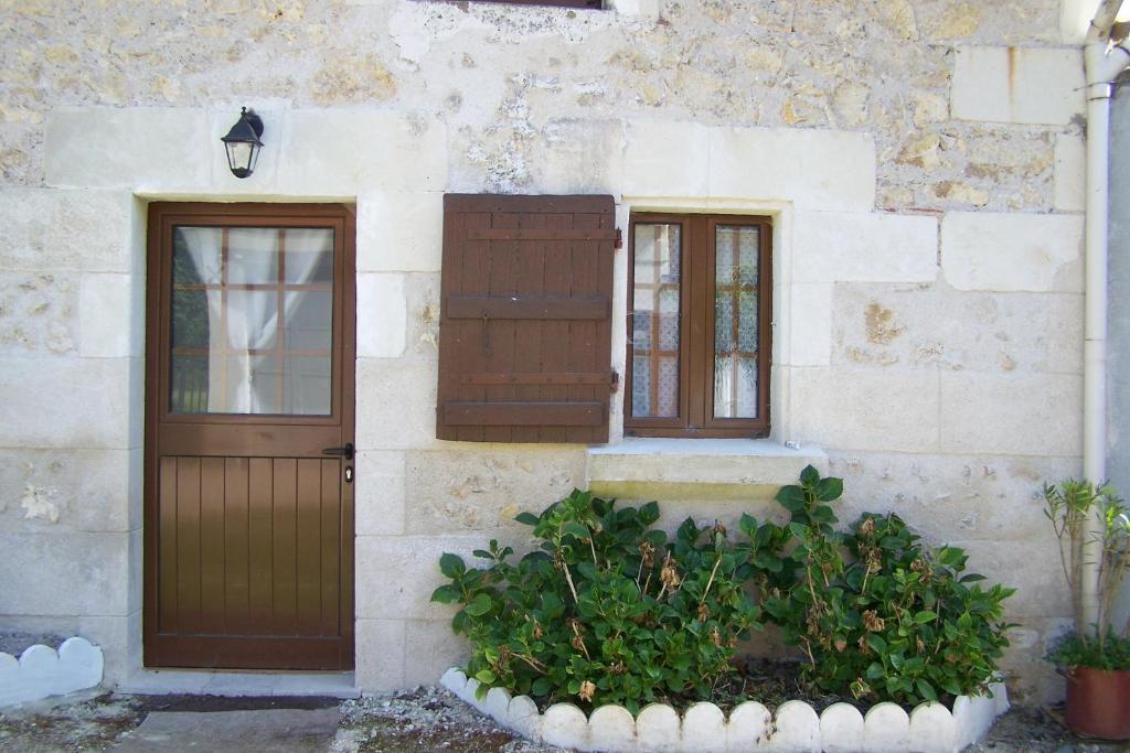 a building with a door and two windows and a plant at petit gite in Rilly-sur-Loire