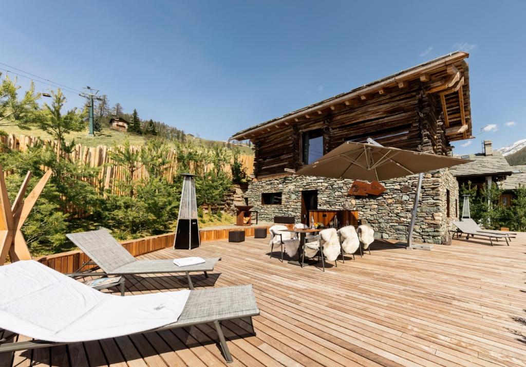 a wooden deck with chairs and an umbrella at Cocoon Deluxe - Luxury Chalet in Chamois