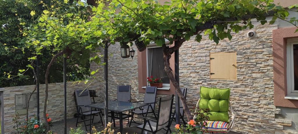 un patio con mesa, sillas y pared de piedra. en Lugas Apartman, en Tapolca