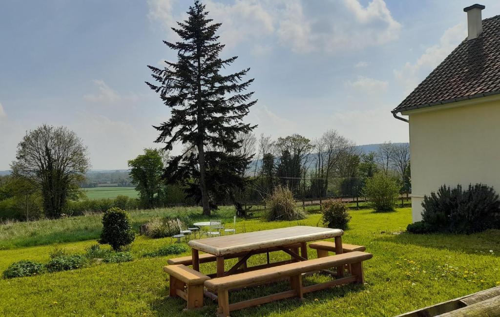 a picnic table in the grass next to a tree at Gîte Cottage chaleureux en pleine campagne vue sur les Monts et Forêts et le château de Carrouges in Carrouges