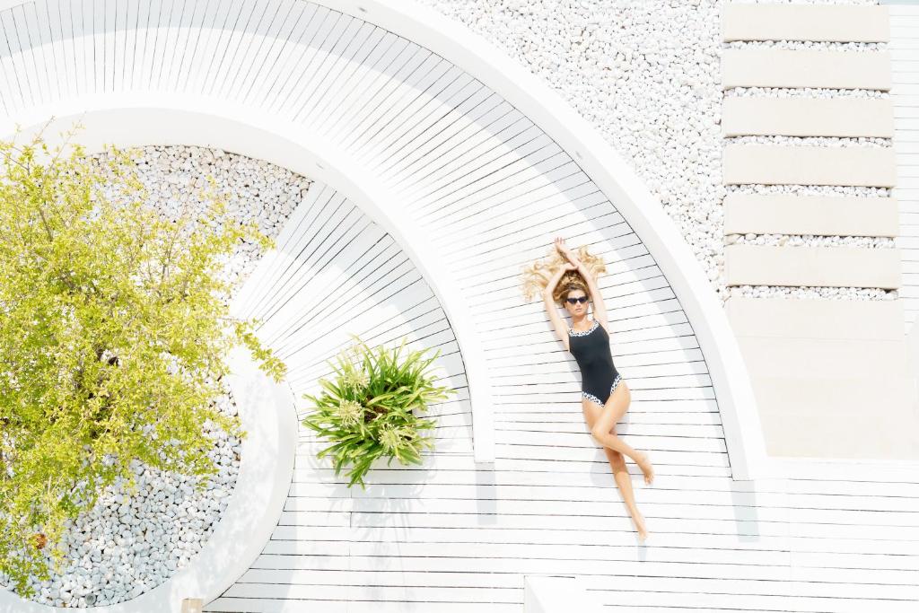 Una donna con un vestito nero che salta su una scala di White Hotel a Vieste