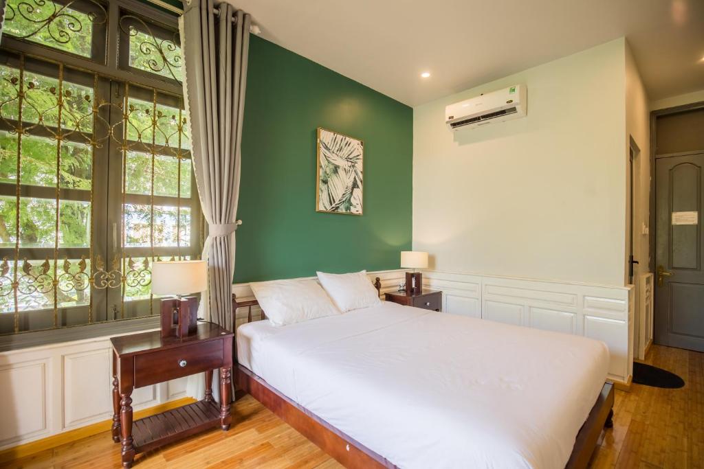 A compact green-accented bedroom with a white bed and barred garden-facing window.