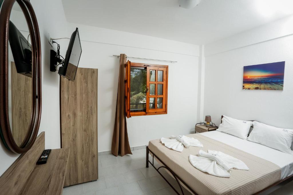 een slaapkamer met een bed en een televisie en een spiegel bij GK Houses #1 in Asprovalta