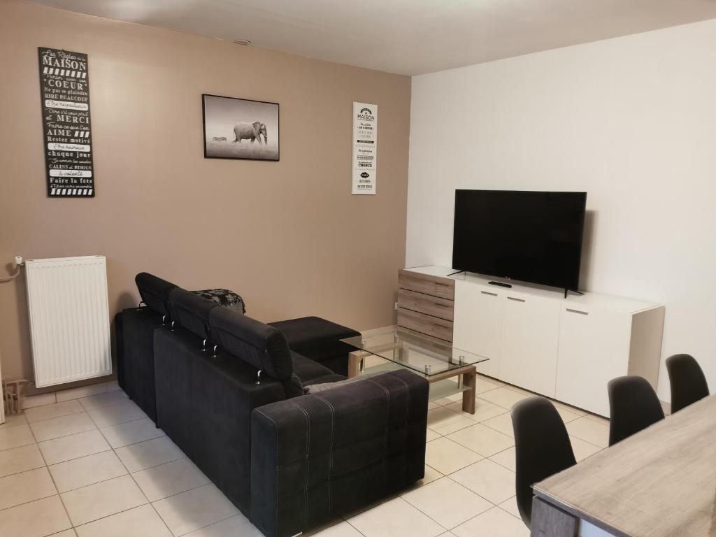 a living room with a couch and a flat screen tv at Agréable maison de 100m2 avec son parking privatif in Calais
