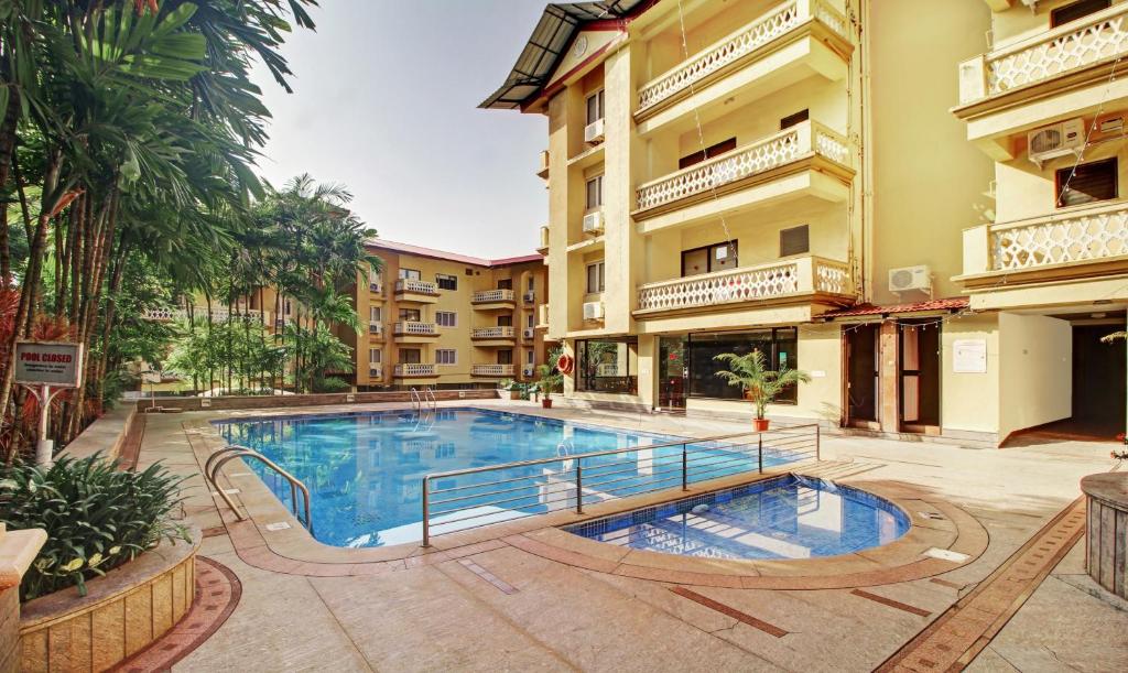 a swimming pool in front of a building at IKIGAI Green Valley Beach Resort in Dona Paula