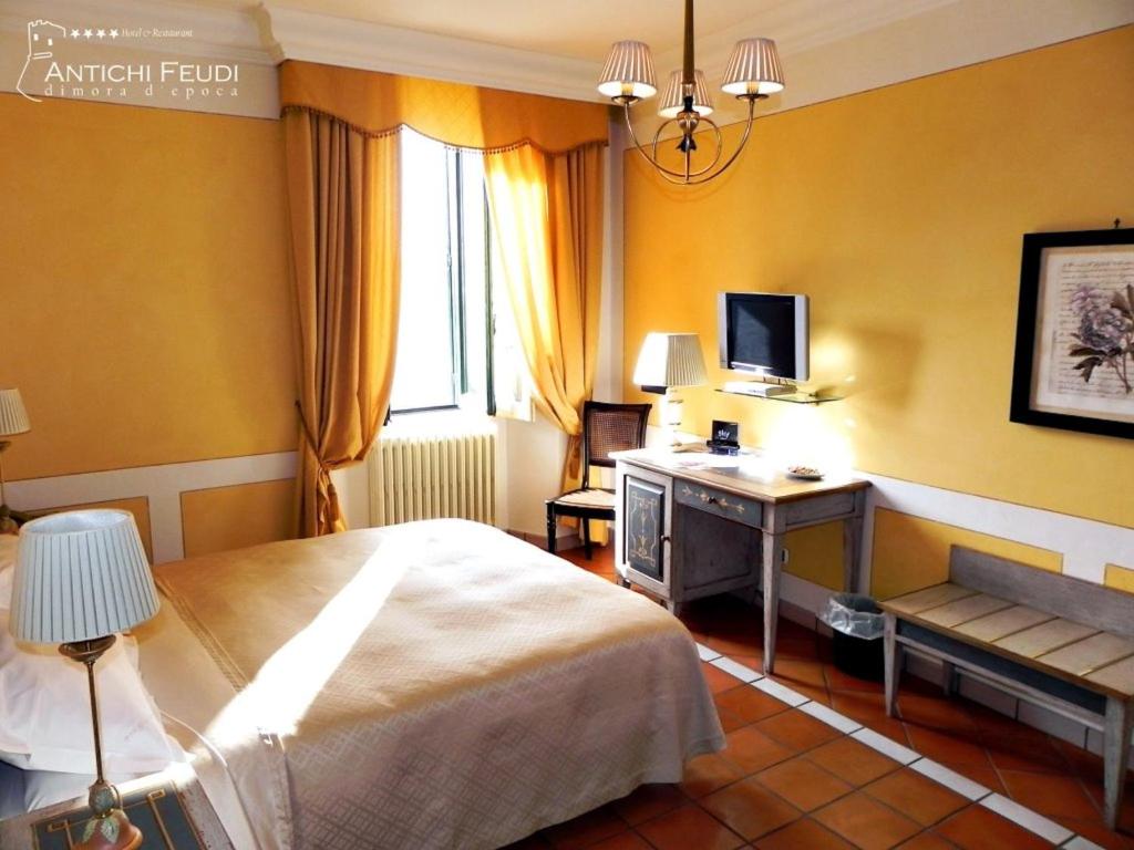 um quarto com uma cama, uma secretária e uma televisão em Antichi Feudi Dimora D'Epoca em Teggiano