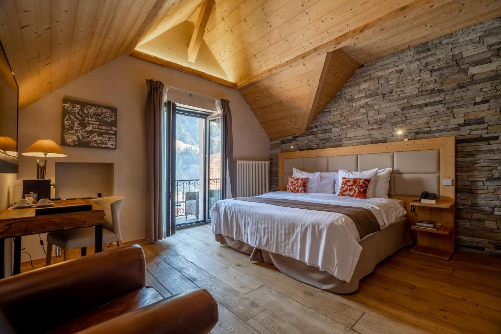 een slaapkamer met een groot bed en een bakstenen muur bij Hôtel National Resort & Spa in Champéry