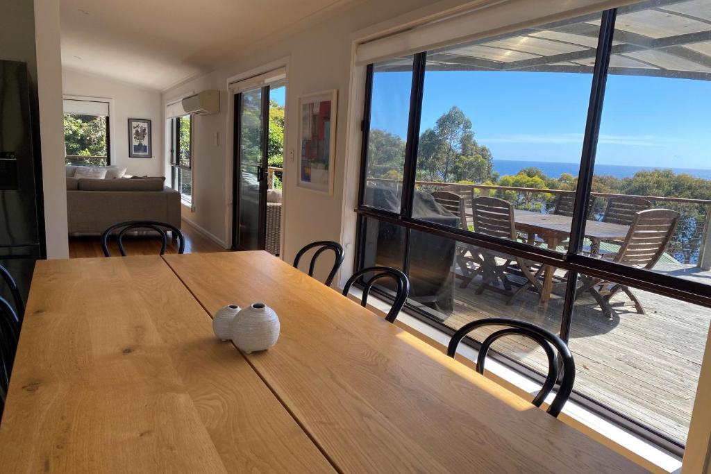 a dining room table with a view of a deck at HIDDEN HAVEN Binalong Bay in Binalong Bay