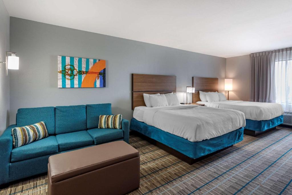 a hotel room with two beds and a couch at MainStay Suites in Bowling Green