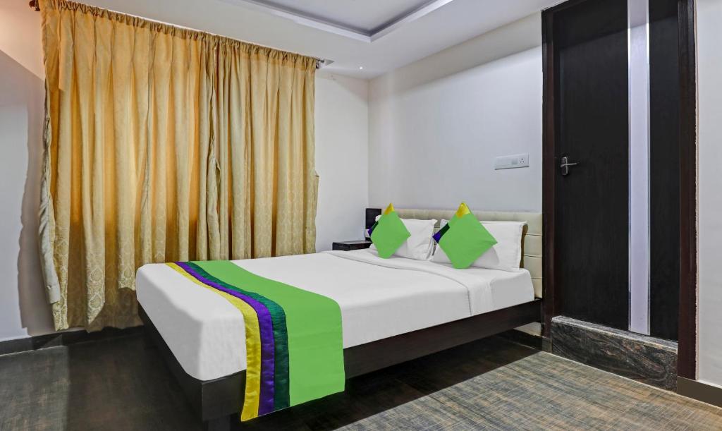 a bedroom with a bed with a green and yellow blanket at Treebo Trend JJ Residency in Bangalore