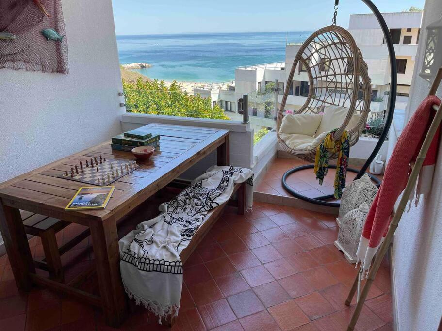 a balcony with a table and a view of the ocean at Lovely 2 bedroom with a pool in front of the beach in Sesimbra