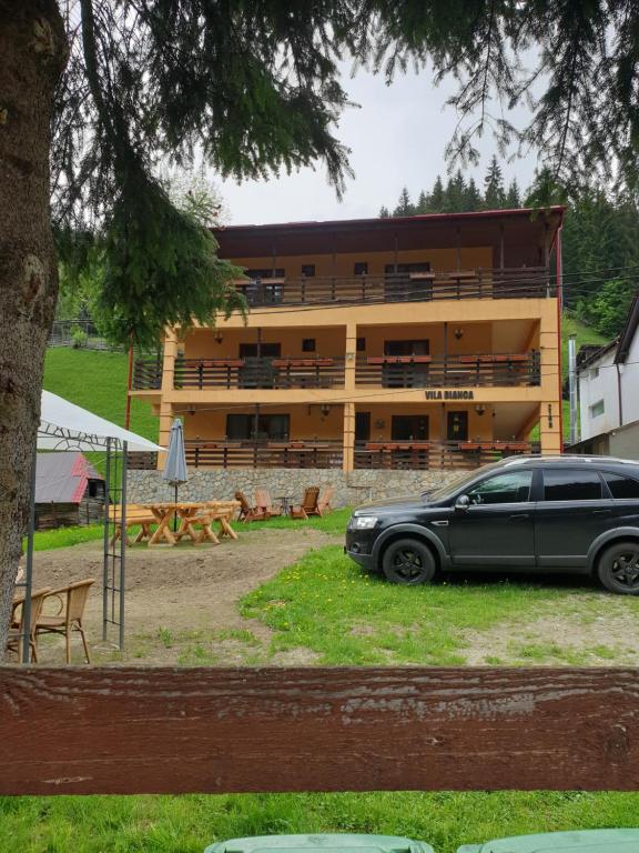 una macchina nera parcheggiata di fronte a un edificio di Vila Bianca Dragusin a Moieciu de Sus