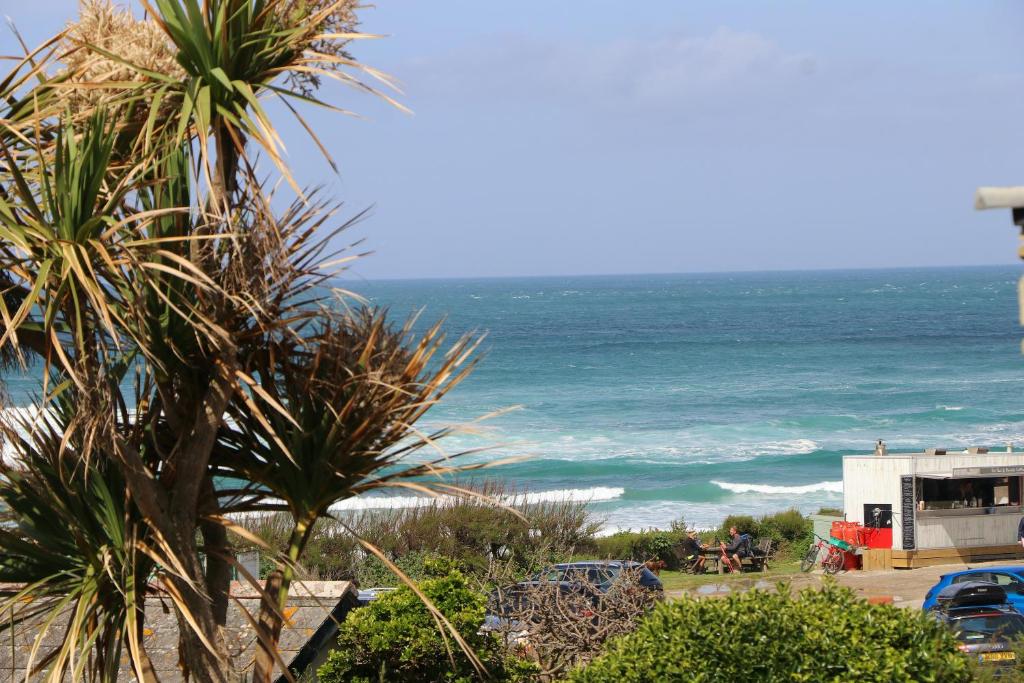 a view of the ocean from a beach with palm trees at STYLISH, BEACHSIDE apartment, sea views in St Merryn