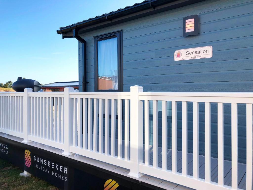 a small blue house with a white fence at Trefalun Park in Tenby