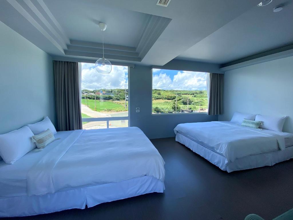 two beds in a bedroom with a large window at 墾丁花見小院Villa包棟民宿 in Eluan