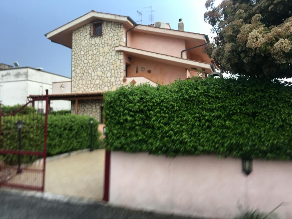 una casa con una siepe di fronte a un edificio di Enza-home-in-ROMA a Borghesiana