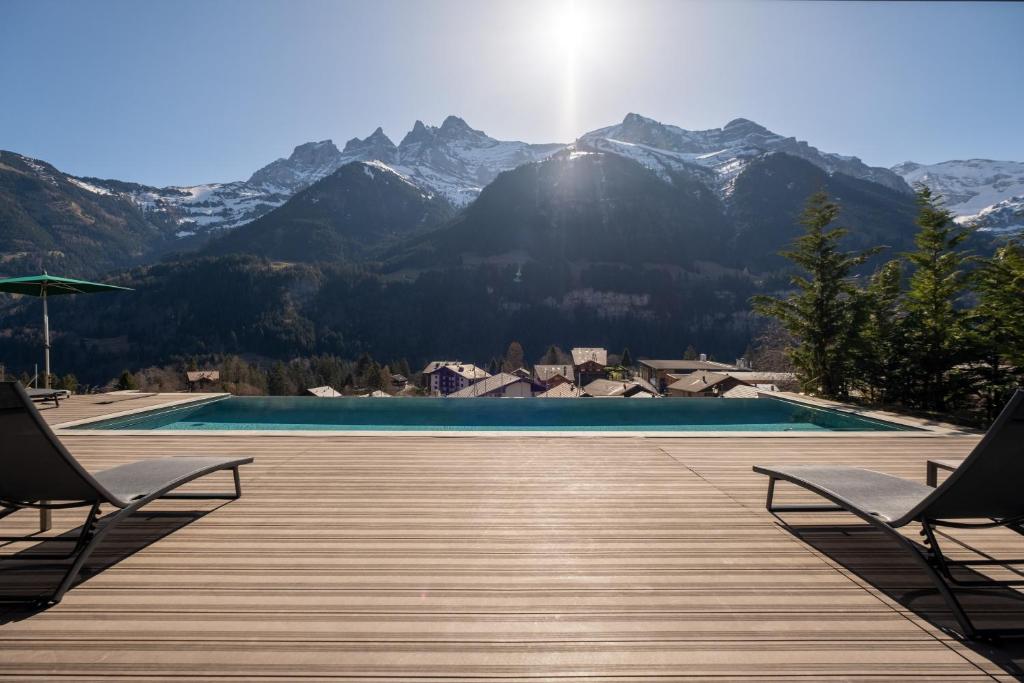 a swimming pool with chairs and mountains in the background at Hôtel National Resort & Spa in Champéry