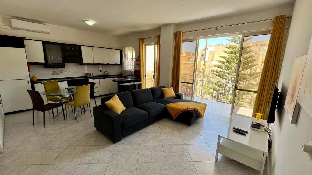 een woonkamer met een bank en een keuken bij Sea view and valley view flat in Marsalforn in Marsalforn