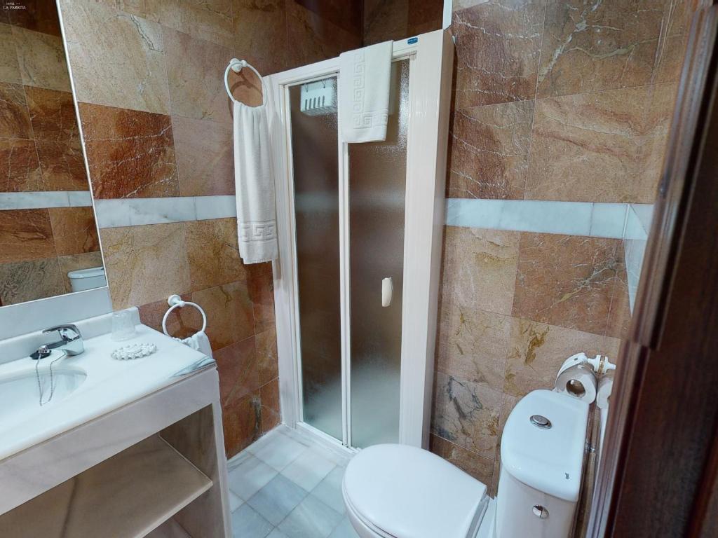 a bathroom with a shower and a toilet and a sink at Hotel La Parrita in Rota