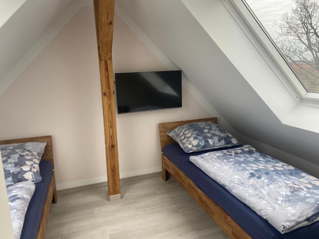 a bedroom with two beds and a tv on the wall at Maisonette-Wohnung An der Weißen Mauer 14 in Görlitz