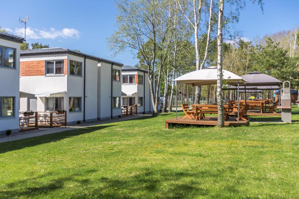 a park with picnic tables and a building at Domki Aqua Holiday in Pobierowo