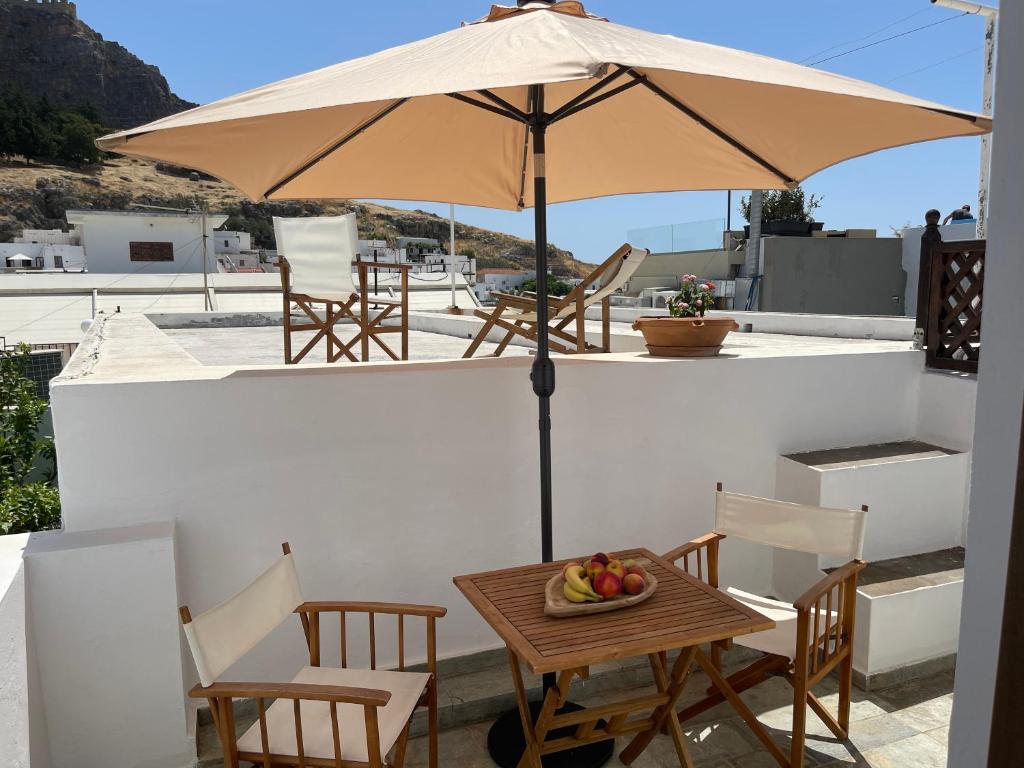 a table and chairs with an umbrella on a roof at Teresa's Home in Líndos