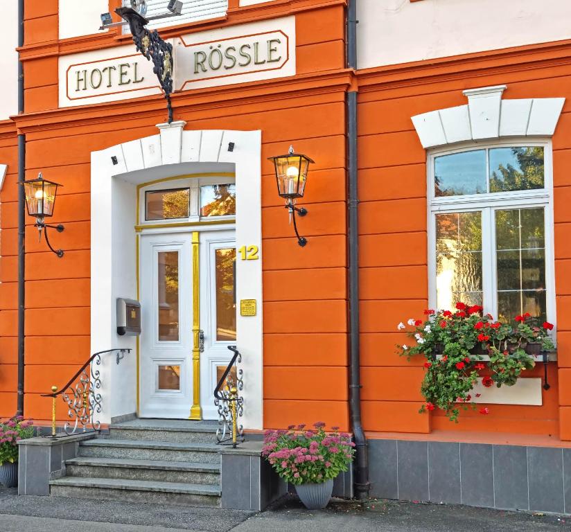 バート・ヴルツァッハにあるGesundheitshotel Rössleの白い扉と花のオレンジ色の建物