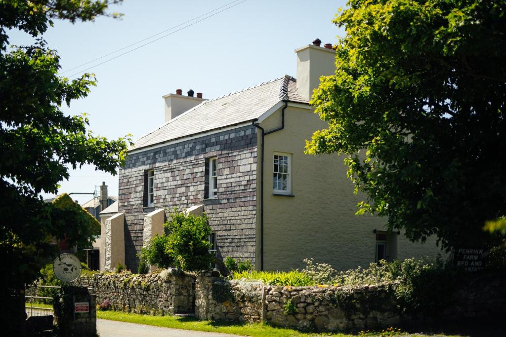 een oud stenen huis met een stenen muur bij Penrhiw Farm B & B in Goodwick