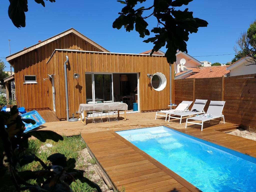 a backyard with a swimming pool and a house at Biby BeachHouse in Lacanau