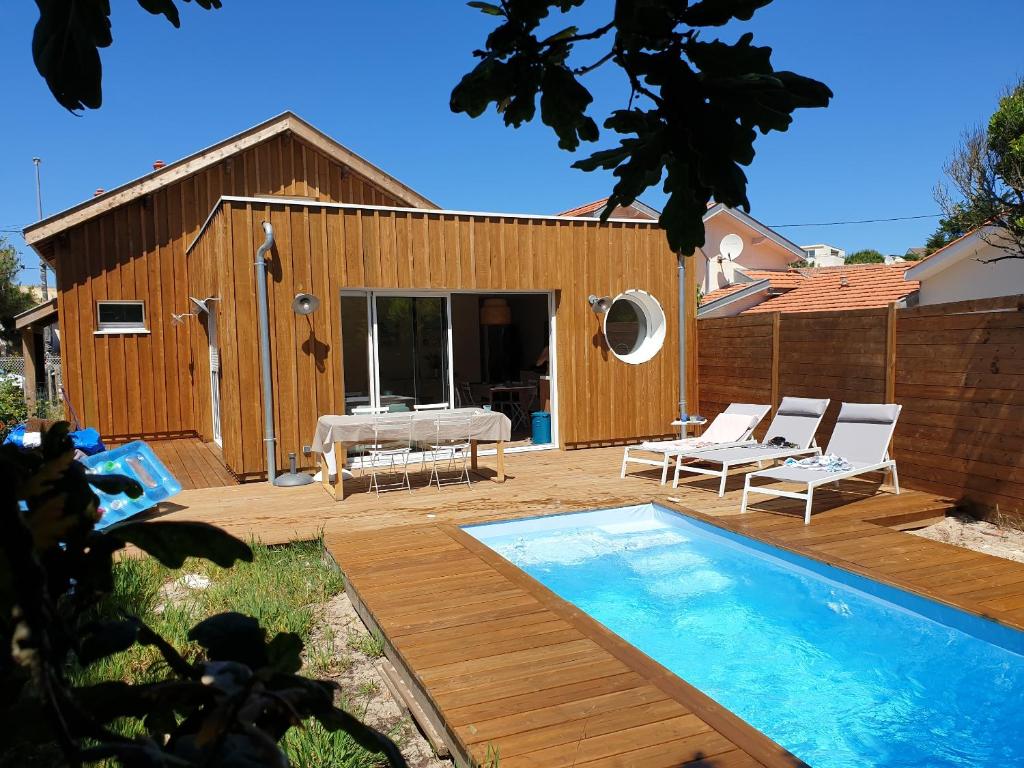 une cour arrière avec une piscine et une maison dans l'établissement Biby BeachHouse, à Lacanau