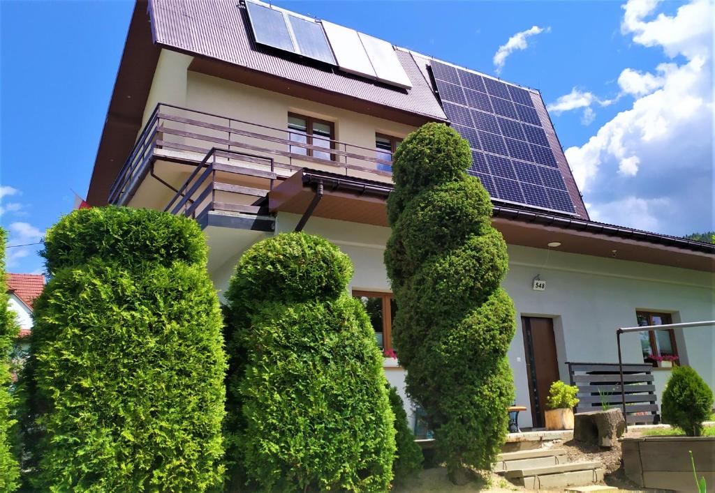 a house with a bunch of bushes in front of a building with solar panels at Agrorelax - Kasina Wielka in Kasina Wielka