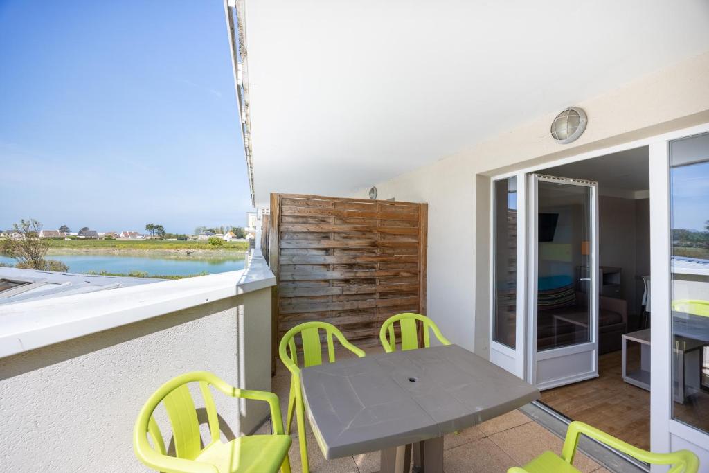 un patio avec une table et des chaises sur un balcon dans l'établissement Le Cormoran, à Courseulles-sur-Mer